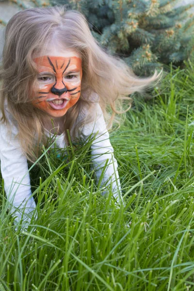 Närbild känslomässiga porträtt av en liten flicka med tiger aqua makeup. Baby morrar som en tiger — Stockfoto