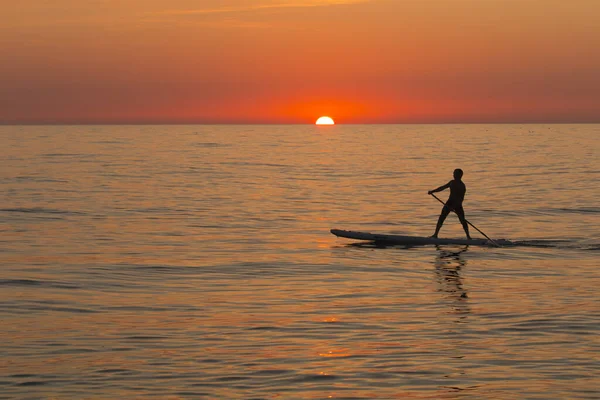 Paddle standing board, beach leisure activity, beautiful silhouette of man at sunset. Romantic colorful sunset at the sea. Sun go down — Stock Photo, Image