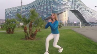 Fitness kızı atletizm pistinde esneme egzersizi yapıyor. Açık havada formda kız eğitimi. yavaş çekim