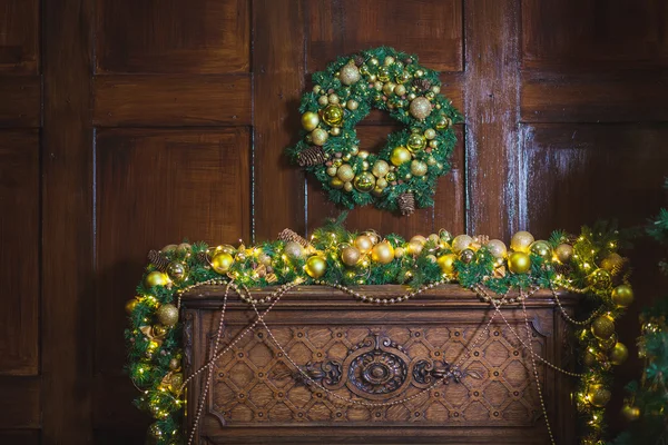 Christmas wreath made of spruce branches, golden balls, cones on the wooden background