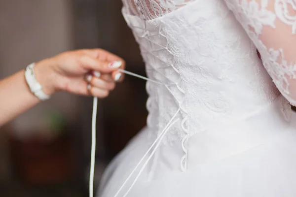 Dama de honra ajudando a amarrar seu vestido de noiva. tradição, a manhã da noiva — Fotografia de Stock