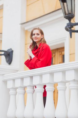 Kırmızı paltolu güzel sarışın kız portresi. Şehir sokak