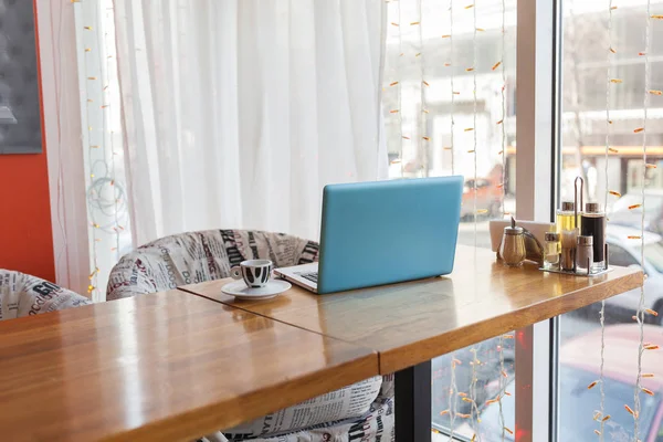 Голубой ноутбук на столе в кофейне — стоковое фото