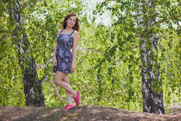 Hermosa chica en un vestido multicolor con pelo largo en el bosque en verano — Foto de Stock