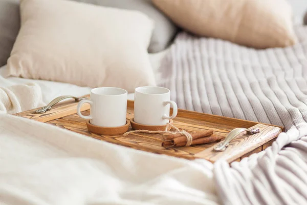 Twee mokken op een dienblad witte bed met een kaneelstokje, Ontbijt concept — Stockfoto