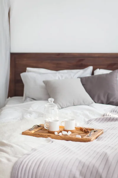 Bir tepsi beyaz iki kupalar tarçın çubuğu, Kahvaltı konsepti ile yatak