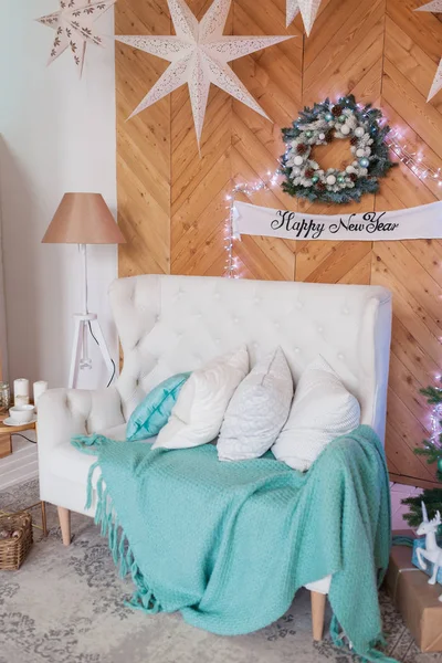 New Years interior in turquoise color. White sofa, Christmas tree with gifts