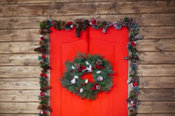 Christmas wreath made of spruce branches, red balls, cones on the wooden background