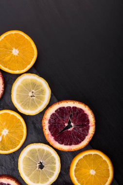 Taze taze sitruslar. Limonlar, kırmızı portakallar ve koyu taş arka planda portakallar. Boşluğu kopyala