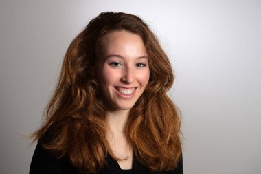 Gülümseyen bir model kadın tasarım saç kesimi, uzun saçlar ve günümüzün kıyafetleriyle kaldı.