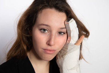 Üzgün esmer kadın, kırık elini yüzüne dayıyor. Beyaz bilek bandajı ve kırık parmağının metal saplantısı olan bir kadın. Elinde stres kırığı var. Ağrı, kazalar ve sağlık hizmetleri kavramı