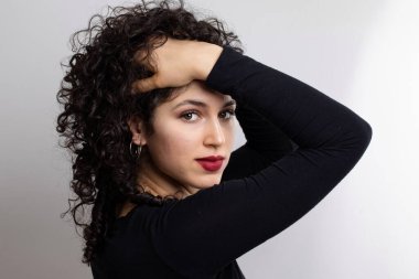 Çekici, kahverengi saçlı kadın kameraya bakıyor. Beyaz kıvırcık saçlı kadın portresi. Beyaz arkaplanda izole