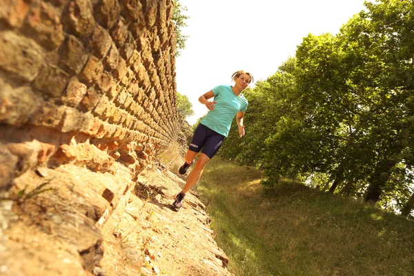 Low angle and skewed view of a woman running along a rural path