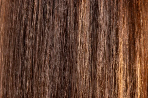 Glossy brown hair texture, background. Close view of long straight women\'s hair. Hair care concept.