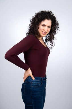 Sırt ağrısından muzdarip, elleri kalçasında bir kızın yarım boy portresi.