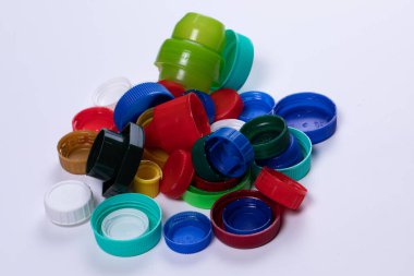 Beyaz arka planda renkli plastik kapaklı kompozisyon. Geri dönüşüm için tasarlanmış vida kapağı yığını. Atık ayıklama ve geri dönüşüm kavramı