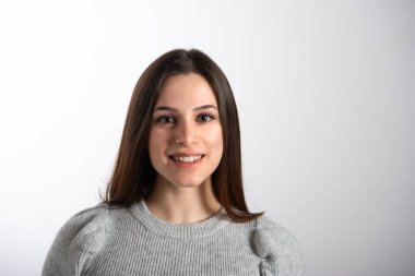 Genç, gülümseyen esmer kadın portresi. Mükemmel temiz ciltli ve uzun kahverengi saçlı bir kadın kameraya bakıyor. Beyaz arkaplanda izole edilmiş, boşluğu kopyala