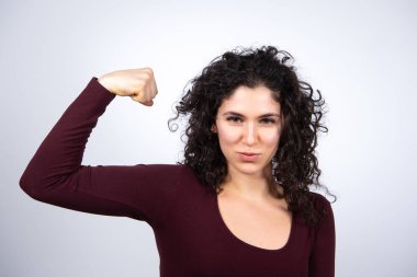 Çekici beyaz esmer kadın el kaslarını gösteriyor. Kaslarını esneten ve kameraya bakan mutlu kadın modelin portresi. Beyaz arkaplanda izole.