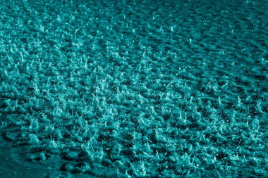 Açık mavi arkaplanlı suda yağmur damlaları.