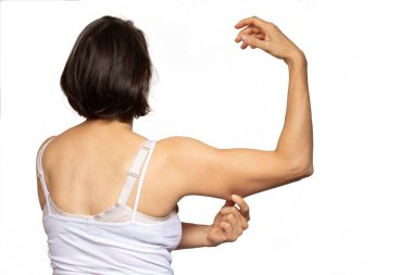 Sırtından sağ kolu havada bir kadın, kolunun ön derisini parmaklarıyla çekiyor.