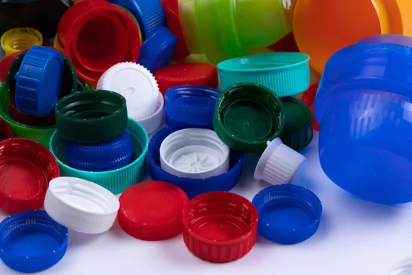 Composition with colourful plastic bottle caps on white background. Pile of screwing lids with thread designated for recycling. Waste sorting and recycle concept