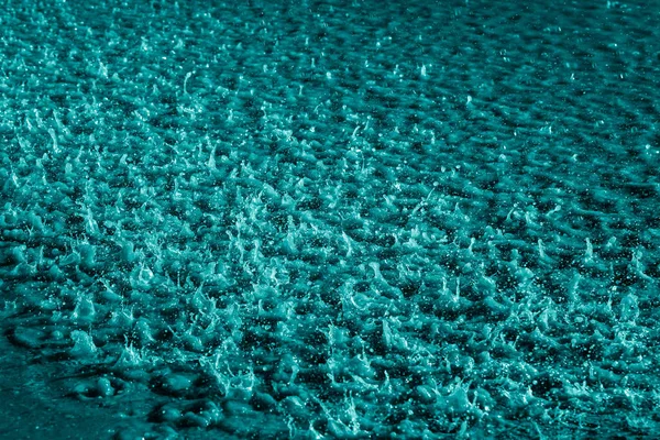 Açık mavi arkaplanlı suda yağmur damlaları.