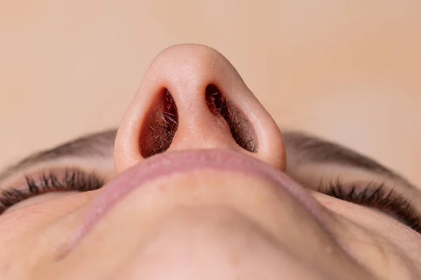 Nose of a woman seen from below. Laser hair removal concept of nose hair