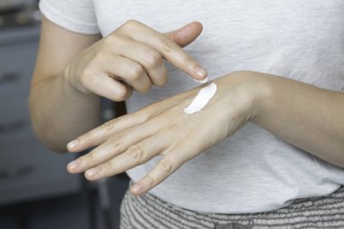 Kafkasyalı genç bir kadının elinin arkasına pahalı bir krem sürerken yakın plan görüntüsü, cilt bakımı ve cilt bakımı..