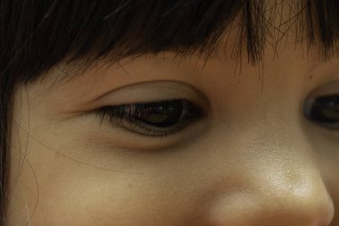 Gözlerde aşırı yakın çekim ve detaylı makro görüş ve sevimli sağlıklı ve mutlu bir çocuğun düğme burun, 3-5 yaşındaki çocuk öğrenme cihazına bakıyor, dağınık saçlı ve koyu kahverengi gözlü..