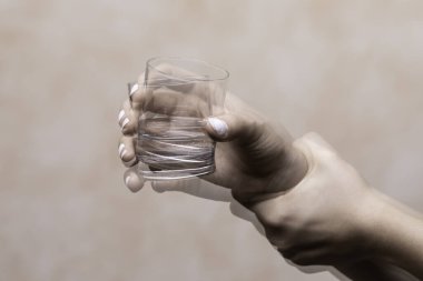 Trembling hand holding glass with alcohol drink clipart