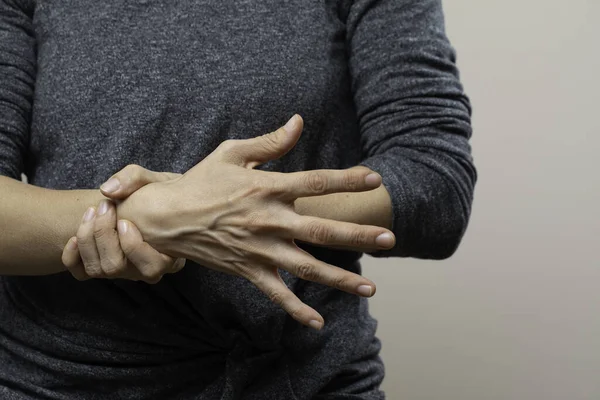 Woman in casual outfit with forearm pain isolated on grey backgr