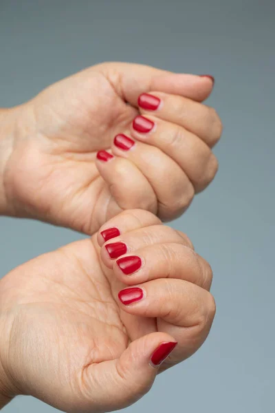 Mãos Femininas Com Manicure Vermelho Isolado Fundo Cinza — Fotografia de Stock