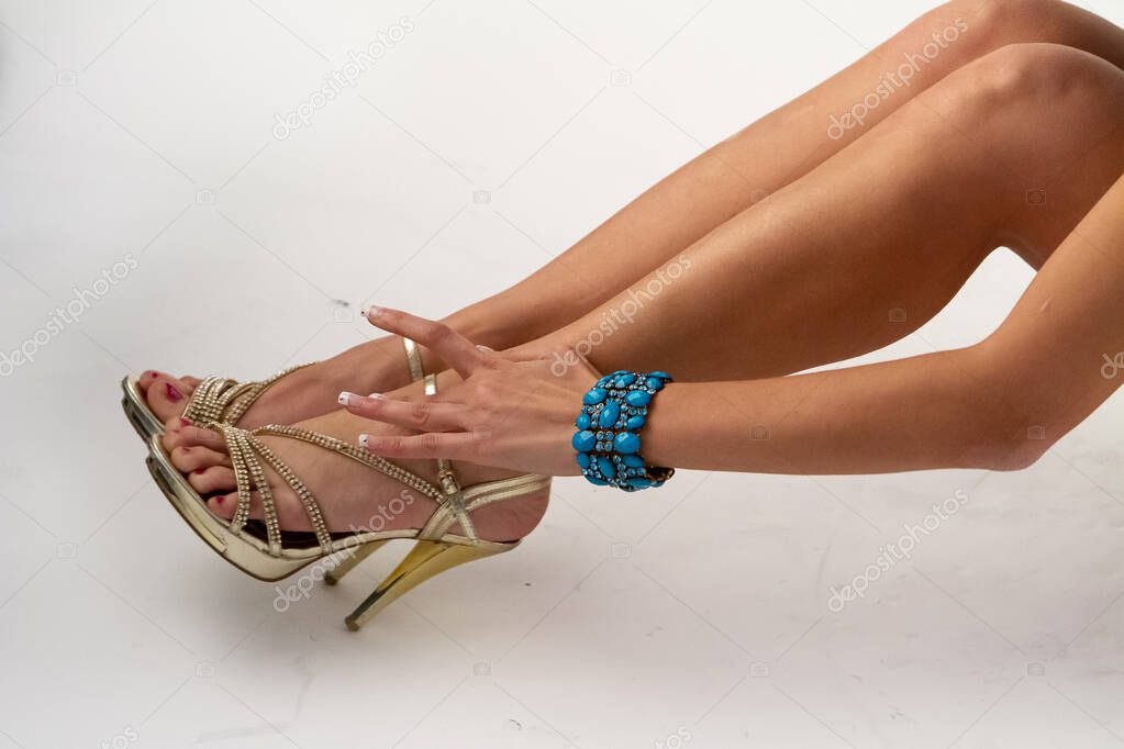 A closeup view on the long nude legs of a gorgeous Caucasian woman, isolated against a white background, wearing elegant high heels.