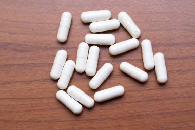 Solunda fotokopi alanı olan koyu tahta bir masada reçeteli ilaç haplarının yukarıdan görünüşü. Sağlık ve tıp kavramları.