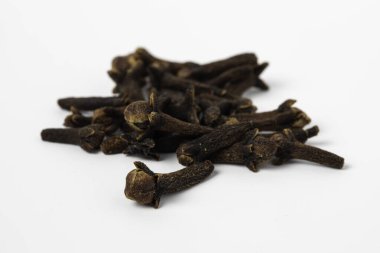 Kurumuş karanfiller beyaz arka planda birikmiş baharatlar.
