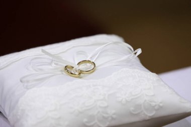 Beyaz bir yastığa bağlanmış bir çift alyans.