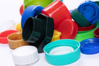 Stüdyodaki beyaz arka planda izole edilmiş parlak ve renkli plastik şişelerin yakın çekim görüntüsü. Tek kullanımlık plastik şişelerde kullanılan çok renkli kapaklar. Atık geri dönüşüm kavramı.