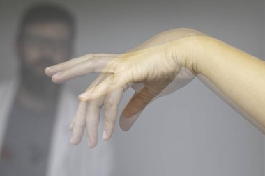Doktor, Parkinson hastası birinin elini sıkıyor.