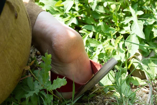 A closeup view on the foot of an active Caucasian woman as she pulls weed from the garden. hardened skin is seen on the sole of the foot with copy-space on the right.