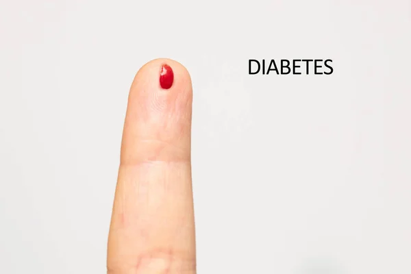 Pricked and bleeding finger is seen close up, diabetes blood glucose level testing, isolated against a white background.