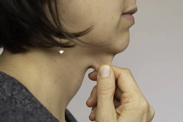 Woman pinching flabby neck skin side view