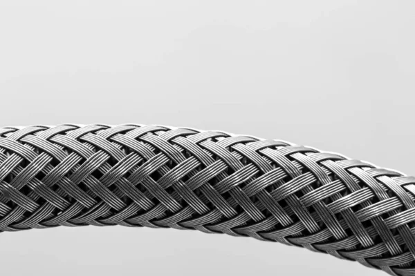 An extreme closeup view of a metallic hose, with criss cross silver strands woven, isolated against a white background with room for copy.