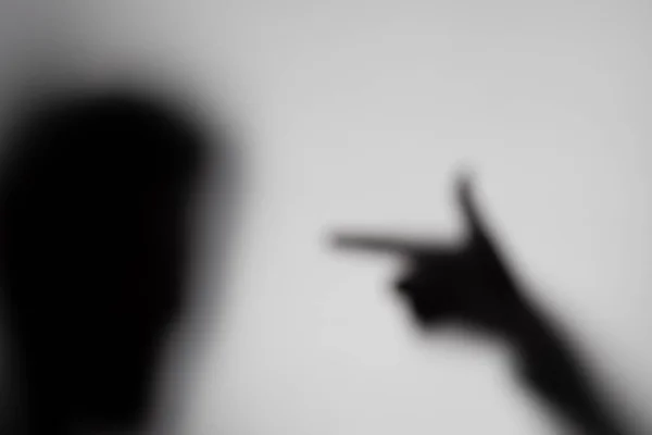 Shadow of a stylized face and a gun-shaped hand