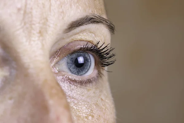 A close up and off to the side view on the eye of a forty year old caucasian woman, healthy blue iris is seen in detail with room for copy.