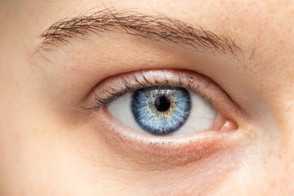 An extreme closeup view on the blue eye of a young Caucasian lady, health and beauty concept.