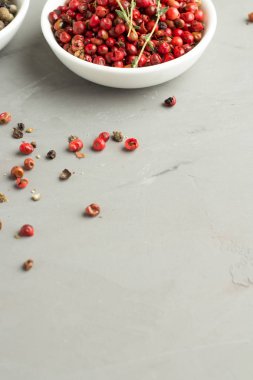 biber ve gri arka plan üzerinde beyaz bir tabak içinde pembe karabiber karışımı