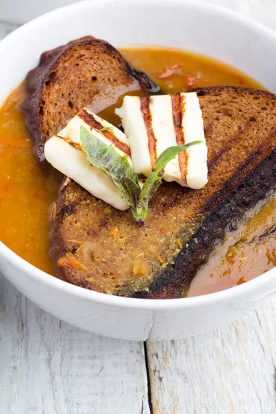 Sopa com pão, queijo e ervas em um fundo de madeira — Fotografia de Stock