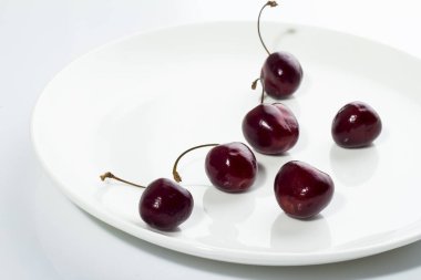 Beyaz bir arka plan üzerinde beyaz bir tabakta kiraz