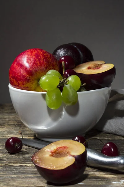 Ahşap bir masa üzerinde beyaz bir tabak meyve