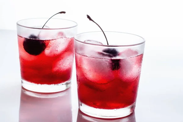 Red drink with a cherry in a glass with ice on a white background — Stock Photo, Image